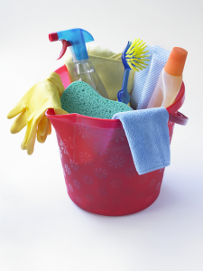 Pink plastic bucket containing cleaning products, including cloths, sponge, and disinfectant bottles