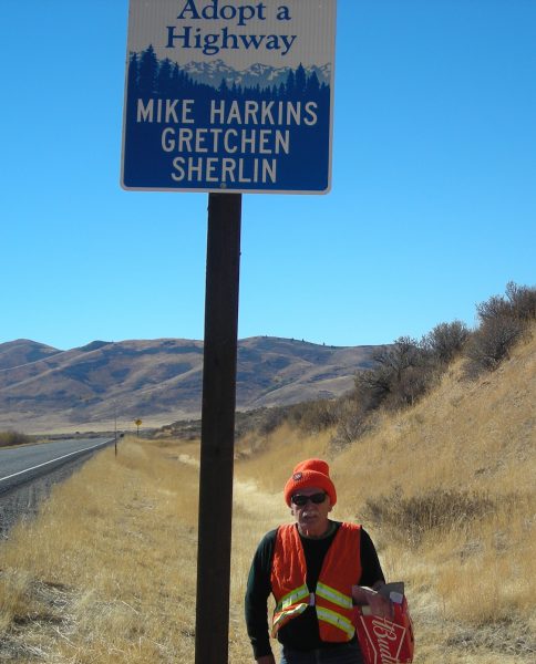 Mike Harkins stands beneath the Adopt-A-Highway sign with his and Gretchen
