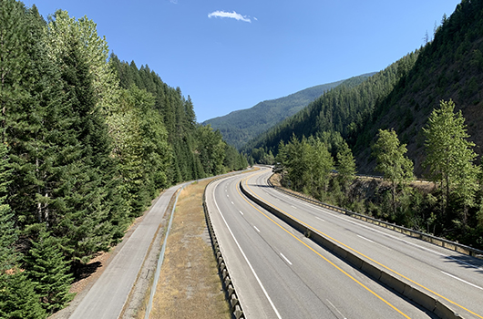 Four lanes of I-90 stretch toward the horizon near Mullan