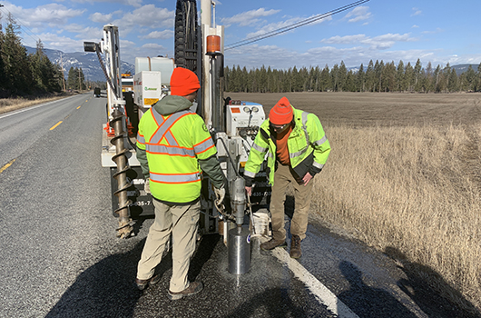 Two workers drill into the highway